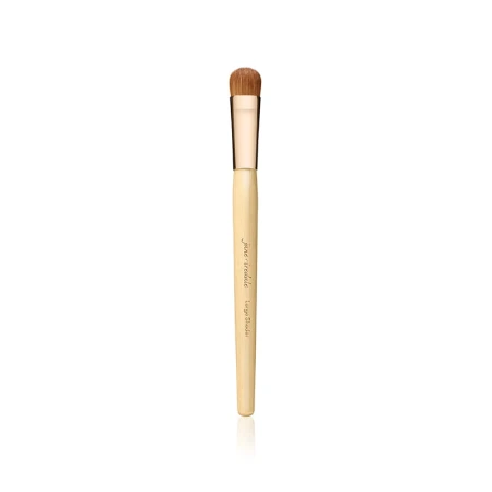 Na zdjęciu widoczny jest pędzel do makijażu marki Jane Iredale. Posiada klasyczny, elegancki wygląd – drewniany trzonek w jasnym kolorze, złota skuwka oraz gęste, miękkie włosie w naturalnym, brązowym odcieniu.