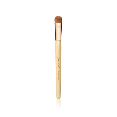 Na zdjęciu widoczny jest pędzel do makijażu marki Jane Iredale. Posiada klasyczny, elegancki wygląd – drewniany trzonek w jasnym kolorze, złota skuwka oraz gęste, miękkie włosie w naturalnym, brązowym odcieniu.
