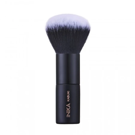 Na zdjęciu widoczny jest pędzel do makijażu typu kabuki marki INIKA Organic. Pędzel ma krótki, czarny trzonek z logo marki i napisem "KABUKI", oraz gęste, zaokrąglone włosie w odcieniach czerni przechodzącej w biel na końcach.