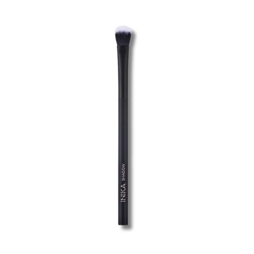 Na zdjęciu znajduje się pojedynczy pędzel do makijażu marki INIKA Organic. Pędzel ma smukły, czarny trzonek z matowym wykończeniem i napisem „INIKA EYESHADOW”, co wskazuje, że jest przeznaczony do aplikacji cieni do powiek.