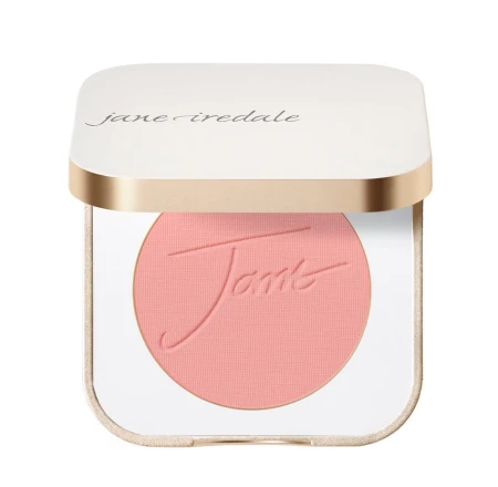 Na zdjęciu widoczny jest róż do policzków jane iredale w odcieniu Queen Bee, zamkniętych w kwadratowym, eleganckim kompakcie z białą pokrywką i złotym wykończeniem.