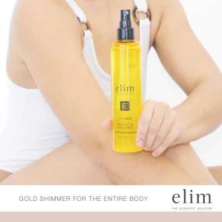 Zdjęcie przedstawia osobę w białym stroju, trzymającą w dłoni złoty spray Elim MEDIHEEL Rejuvenating Gold Spritz. Na dole grafiki widnieje napis: „GOLD SHIMMER FOR THE ENTIRE BODY” oraz logo elim z hasłem „THE SCIENTIFIC SOLUTION”.