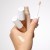 Na zdjęciu widać dłoń trzymającą trzy korektory PureMatch Liquid Concealer w różnych odcieniach. Jeden z korektorów ma odkręconą nakrętkę i aplikator z gąbeczką. Na wierzchu dłoni znajdują się próbki kolorów – jeden bardzo jasny, drugi bardziej beżowy.