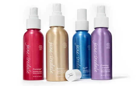 Na zdjęciu widac 4 nawilżające wody utrwalające makijaż Jane Iredale: POMMISST, BALANCE, D2 i Lavender. Butelki ułożone są obok siebie.