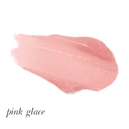 Na zdjęciu widoczna jest rozsmarowana próbka błyszczyka lub pomadki w odcieniu Pink Glace. Kolor to delikatny, jasnoróżowy z subtelnym połyskiem i drobinkami brokatu, które nadają mu efekt rozświetlenia.