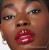 Na zdjęciu widzimy modelkę noszącą błyszczyk do ust Jane Iredale w odcieniu Siren. Usta modelki pokryte są intensywnie czerwonym błyszczykiem o wysokim połysku. Ten odcień świetnie podkreśla urodę i dodaje charakteru