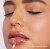 Na zdjęciu widzimy modelkę aplikującą błyszczyk do ust Jane Iredale w odcieniu Nectar. Usta modelki mają subtelny, brzoskwiniowo-beżowy odcień z połyskiem, który dodaje świeżości i naturalnego blasku.