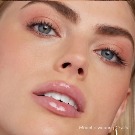 Na zdjęciu widzimy modelkę noszącą błyszczyk do ust Jane Iredale w odcieniu Crystal. Usta modelki są pokryte przezroczystym błyszczykiem, który nadaje im efektowny połysk i lekko wilgotny wygląd.