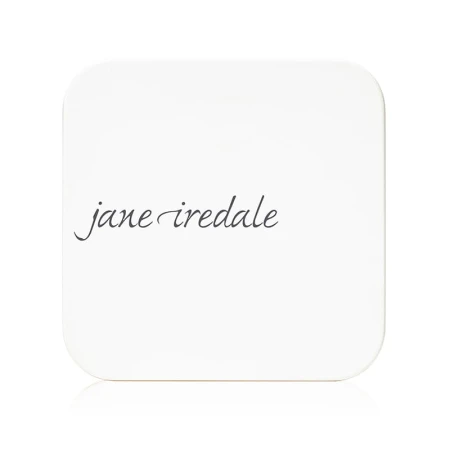 Na zdjęciu jest zamknięte, kompaktowe opakowanie do pudru wielokrotnego użytku marki jane iredale.  Minimalistyczny, elegancki design w kolorze białym z logiem marki.