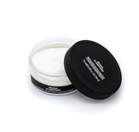 Otwarty słoiczek odżywki do włosów Davines OI Conditioner o pojemności 75 ml. W środku widoczna biała, kremowa konsystencja produktu. Pokrywka z czarną etykietą oparta o pojemnik.