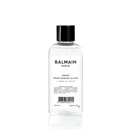 Przezroczysta butelka z czarną nakrętką zawierająca 100 ml eliksiru nawilżającego z olejem arganowym marki Balmain Paris. Etykieta w minimalistycznym stylu, czarny tekst na białym tle.