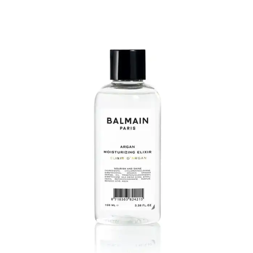 Przezroczysta butelka z czarną nakrętką zawierająca 100 ml eliksiru nawilżającego z olejem arganowym marki Balmain Paris. Etykieta w minimalistycznym stylu, czarny tekst na białym tle.
