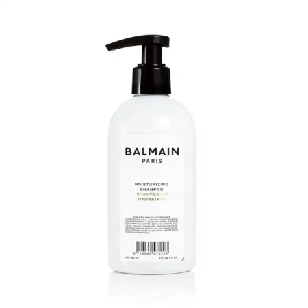 Biała butelka z czarną pompką zawierająca szampon nawilżający Balmain Paris Moisturizing Shampoo. Elegancki, minimalistyczny design. Produkt o pojemności 300 ml przeznaczony do pielęgnacji suchych lub farbowanych włosów.