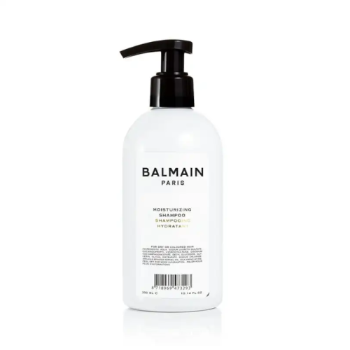 Biała butelka z czarną pompką zawierająca szampon nawilżający Balmain Paris Moisturizing Shampoo. Elegancki, minimalistyczny design. Produkt o pojemności 300 ml przeznaczony do pielęgnacji suchych lub farbowanych włosów.
