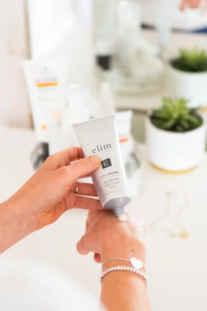 Kobieta aplikuje Elim MEDIHAND Age Reversal Hand Cream SPF30 na grzbiet dłoni.