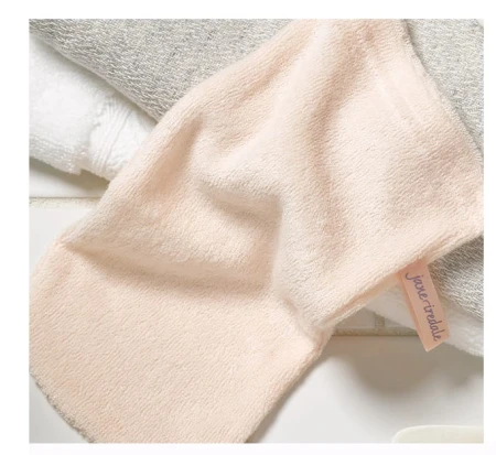 Na zdjęciu jest rękawica Magic Mitt marki Jane Iredale – wykonana z miękkiego, delikatnego materiału o jasnoróżowym kolorze. Posiada metkę z nazwą marki.