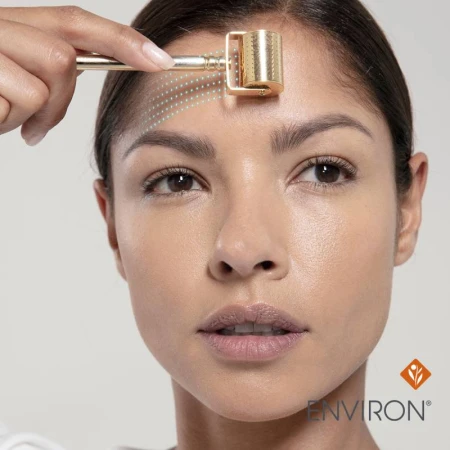 Zbliżenie na twarz kobiety trzymającej Cosmetic Gold Roll - Cit. Na czole zaznaczone są graficznie rekomendowane ruchy stempla. Na czole zaznaczone są graficznie rekomendowane ruchy rollera.