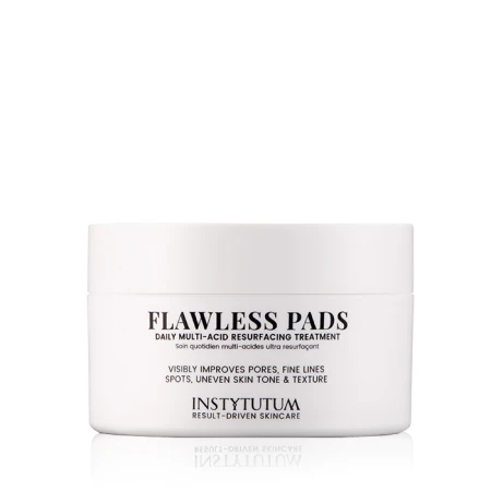 Na zdjęciu znajduje się elegancki biały pojemnik z produktem kosmetycznym Instytutum Flawless Pads. Opakowanie ma minimalistyczny design z czarnym napisem. Produkt przeznaczony jest do codziennego złuszczania skóry.