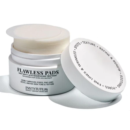 Na zdjęciu pokazane jest otwarte opakowanie kosmetyku Flawless Pads marki Instytutum. Wewnątrz widoczne są okrągłe, nasączone płatki do codziennego złuszczania skóry. Pokrywka leży obok, ukazując estetyczny nadruk z opisem działania produktu.