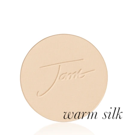 Okrągły, prasowany puder do twarzy marki Jane Iredale w odcieniu Warm Silk: jasny beż z ciepłym, złocistym podtonem z wytłoczonym logo Jane Iredale.