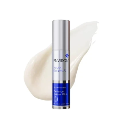 Butelka kremu ENVIRON Antioxidant Defence Creme Plus w kolorze srebrnym, ze srebrną nakrętką i granatową etykietą, na tle próbki tego produktu w formie białej, rozsmarowanej kropli kremu.