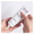 Dwie dłonie trzymają tubkę Instytutum Transforming Melting Cleanser. Jedna wyciska produkt na dłoń. Tubka biała z czarnym napisem, zawiera oczyszczający i nawilżający żel z kwasem hialuronowym, olejem migdałowym i witaminami.