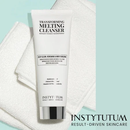 Biała tubka Instytutum Transforming Melting Cleanser leży na białym ręczniku, na tle w kolorze miętowym. Produkt oczyszczający i nawilżający z kwasem hialuronowym, olejem migdałowym i witaminami. W prawym dolnym rogu logo marki Instytutum.