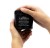 Ręce trzymające czarny słoik kosmetyku Davines OI Hair Butter o pojemności 250 ml. Produkt przeznaczony do pielęgnacji włosów, etykieta w kolorze czarnym z białym napisem. Tło białe.