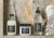 Trzy kosmetyki do włosów marki Davines ustawione na marmurowej półce: OI Shampoo, OI Conditioner oraz Liquid Luster – każdy w charakterystycznym opakowaniu z czarną etykietą, na tle kamiennej ściany o naturalnym wzorze.