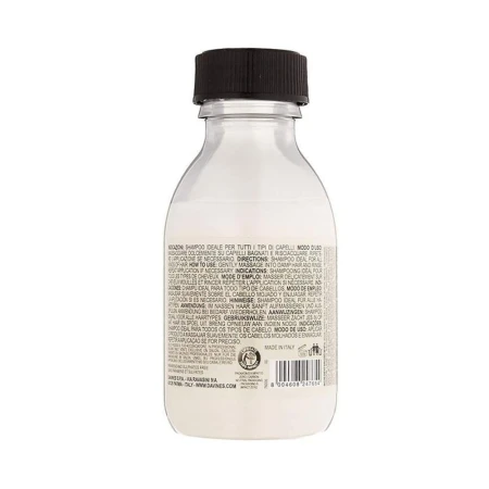 Tylna etykieta butelki szamponu Davines OI Shampoo z tekstem w wielu językach, informującym o sposobie użycia i właściwościach produktu; widoczna czarna zakrętka i kod kreskowy na dole.
