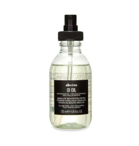Butelka Davines OI Oil – Absolute Beautifying Potion o pojemności 135 ml. Przezroczyste opakowanie z czarną pompką i czarną etykietą zawiera lekkie, złociste serum do włosów z olejkiem roucou, przeznaczone do wszystkich rodzajów włosów.
