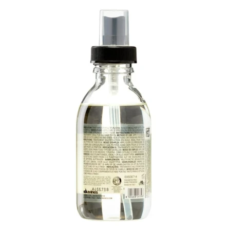 Tył butelki Davines OI Oil – Absolute Beautifying Potion o pojemności 135 ml. Przezroczyste opakowanie z czarną pompką i etykietą zawierającą szczegóły produktu, skład oraz kod kreskowy. Widoczny poziom jasnożółtego olejku wewnątrz butelki.