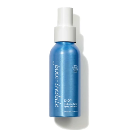Na zdjęciu znajduje się elegancka, niebieska butelka z białym atomizerem wody Jane Iredale D2O Hydration Spray o pojemności 90 ml. Produkt posiada oznaczenie ECOCERT co potwierdza jego organiczne i naturalne pochodzenie składników.