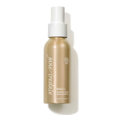 Na zdjęciu znajduje się elegancka złota butelka z białym atomizerem wody Jane Iredale  Balance Hydration Spray o pojemności 90 ml. Produkt posiada oznaczenie ECOCERT co potwierdza jego organiczne i naturalne pochodzenie składników.