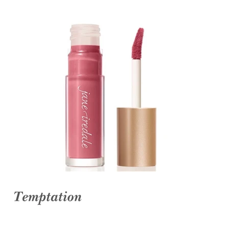 Na zdjęciu widoczny jest błyszczyk do ust Jane Iredale w odcieniu Temptation. Produkt ma matowe wykończenie i prezentuje się w ciepłym, różowym kolorze z lekkim odcieniem brzoskwini. Opakowanie jest przezroczyste, co pozwala zobaczyć kolor kosmetyku