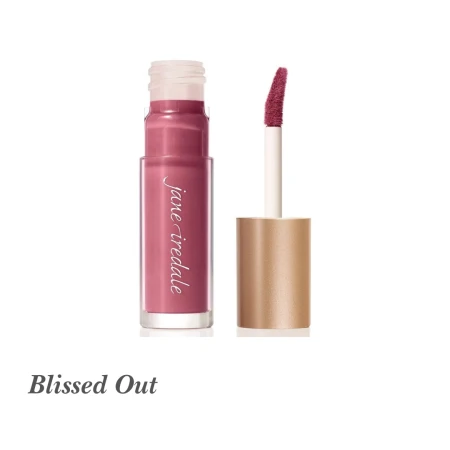 Na zdjęciu widoczny jest błyszczyk do ust Jane Iredale w odcieniu Blissed Out. Opakowanie zawiera klasyczny aplikator z gąbeczką i złotą zakrętką. Kolor Blissed Out to stonowany, chłodny odcień różu z domieszką fioletu