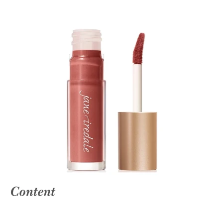 Na zdjęciu widoczny jest błyszczyk do ust Jane Iredale w odcieniu Content. Produkt ma eleganckie opakowanie z przezroczystym pojemniczkiem i złotą nakrętką z aplikatorem w formie gąbeczki. Odcień Content to ciepły, brązowy nude z delikatnym różowym tonem