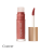 Na zdjęciu widoczny jest błyszczyk do ust Jane Iredale w odcieniu Content. Produkt ma eleganckie opakowanie z przezroczystym pojemniczkiem i złotą nakrętką z aplikatorem w formie gąbeczki. Odcień Content to ciepły, brązowy nude z delikatnym różowym tonem