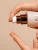 Zdjęcie przedstawia aplikację INIKA Adaptogenic Cleansing Oil – olejku oczyszczającego o lekkiej, oleistej konsystencji. Widzimy przezroczysty olejek spływający na palce, co podkreśla jego delikatną formułę
