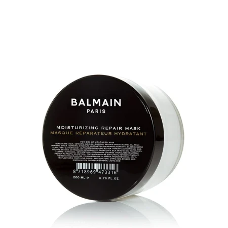 Na zdjęciu widoczna jest nawilżająca maska regenerująca do włosów Balmain Paris – Moisturizing Repair Mask. Produkt znajduje się w eleganckim, przezroczysto-białym słoiczku z czarnym, błyszczącym wieczkiem.