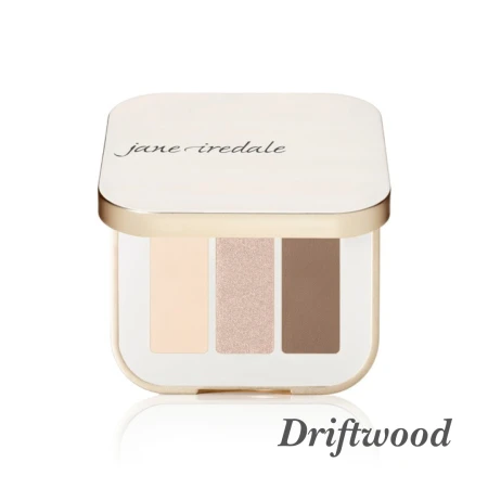 Na zdjęciu  jest potrójna paleta cieni do powiek marki jane iredale w odcieniu Driftwood. Paleta zawiera trzy odcienie w neutralnej tonacji:  jasny, beżowy odcień,  średni, szampański odcień z połyskiem,  ciemniejszy, chłodny brązowy odcień.