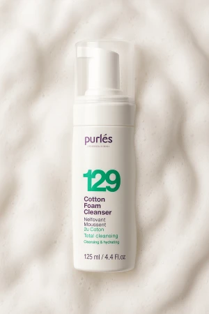Na zdjęciu jest kosmetyk Purles – Cotton Foam Cleanser 129. W tle znajduje się puszysta, biała piana.