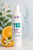Na zdjęciu widoczna butelka Purles – 118 Gentle Toner. To produkt w białym, smukłym opakowaniu z pompką i przezroczystą nakrętką. W tle widać owoc pomarańczy i krople wody.