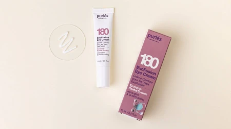 Po lewej stronie znajduje się tubka kremu pod oczy 180 ExoFusion Eye Cream o poj.15 ml w kolorze białym, obok niej fioletowe pudełko. Obok, na okrągłej przezroczystej płytce, jest próbka kremu w formie białej, gładkiej emulsji.