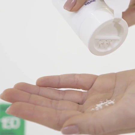 Na zdjęciu widać dłoń, na którą ktoś wysypuje niewielką ilość białego pudru z opakowania produktu kosmetycznego marki Purlés. To Enzymatic Face Powder 150. Produkt w formie sypkiej, po kontakcie z wodą zamienia się w lekką piankę.