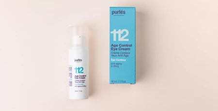 Po lewej stronie znajduje się butelka kremu pod oczy 112 Age Control Eye Cream o poj.30 ml w kolorze białym, obok niej turkusowe pudełko. Oba produkty są na jasno różowym tle.
