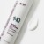 Na zdjęciu jest biała butelka produktu PURLES 140 Retinol Night Cream, leżąca na jasnym tle. Obok znajduje się próbka kremu w formie gładkiej, białej smugi, co pokazuje jego konsystencję – lekką i kremową. Na opakowaniu widoczny jest numer „140”.