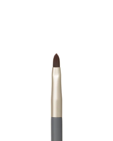 Na zdjęciu jest zbliżenie na pędzelek do ust z kolekcji jane iredale. Ma precyzyjny, spiczasty kształt włosia, który umożliwia dokładne obrysowanie konturu ust i równomierne wypełnienie ich kolorem.
