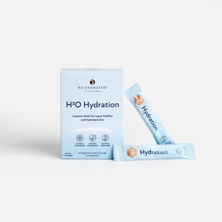 Zdjęcie przedstawia stojące biało-błękitne pudełko suplementu diety w proszku Rejuvenated H3O Hydration. Na pierwszym planie znajdują się również dwie, identyczne, niebieskie saszetki z produktem, z których jedna jest lekko przechylona
