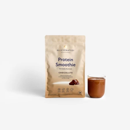 Myślę Szukam Zdjęcie przedstawia stojące, beżowe, zamykane strunowo opakowanie proszku Rejuvenated Protein Smoothie o smaku czekoladowym. Obok niego, po prawej stronie, stoi przezroczysta szklanka wypełniona gotowym napojem. Tło jest jasnoszare.